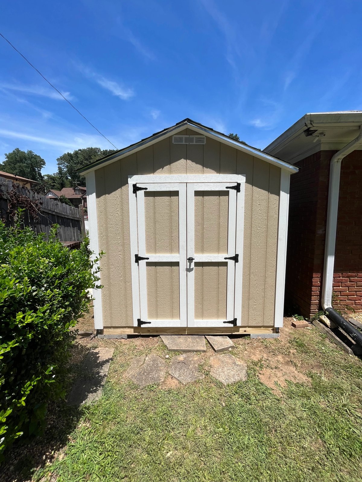 Beige gable shed built on-site in a tight spot beside a home